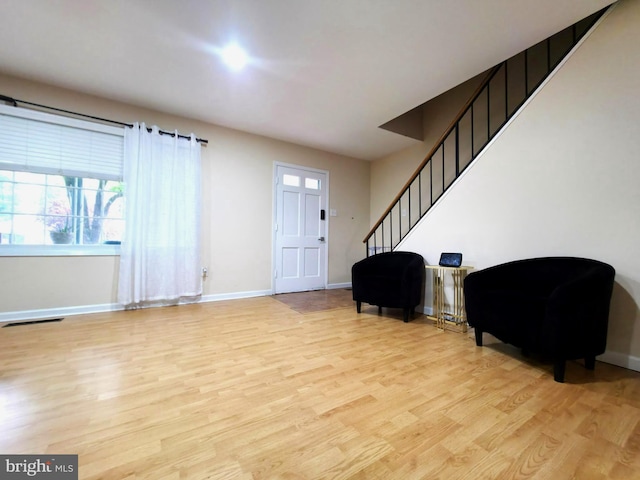 entrance foyer with light wood-type flooring, stairway, baseboards, and plenty of natural light