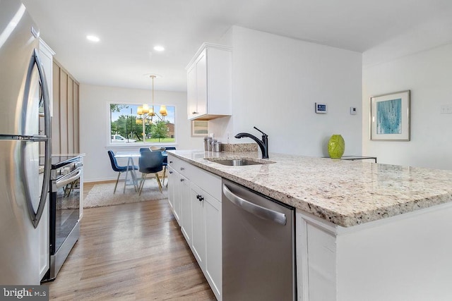 1214 Barnaby Ter SE, Washington, DC 20032 - kitchen with appliances with stainless steel finishes, a sink, light wood finished floors, a chandelier, and white cabinetry