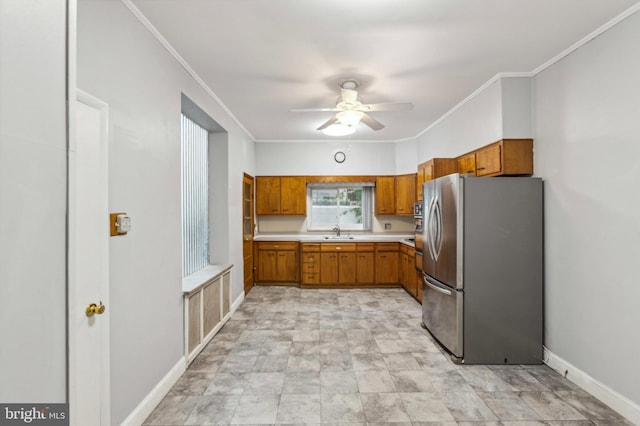 kitchen with freestanding refrigerator, light countertops, a ceiling fan, a sink, and brown cabinetry