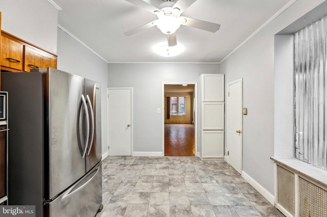 kitchen with freestanding refrigerator, ornamental molding, a ceiling fan, baseboards, and brown cabinetry