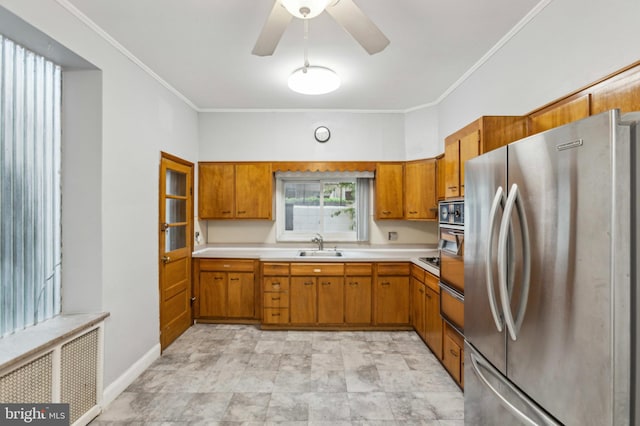 kitchen featuring freestanding refrigerator, brown cabinetry, light countertops, a sink, and crown molding