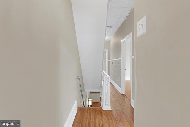 hall with an upstairs landing, wood finished floors, and baseboards
