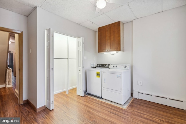 laundry area featuring cabinet space, baseboard heating, washer and dryer, light wood-style flooring, and ceiling fan