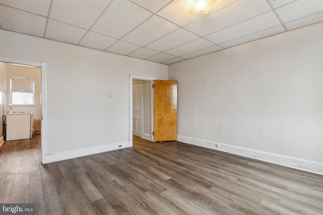 unfurnished room featuring a drop ceiling, wood finished floors, and baseboards