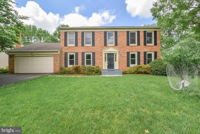 colonial-style house with a garage, asphalt driveway, brick siding, and a front lawn