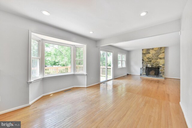unfurnished living room with light wood-type flooring, a fireplace, baseboards, and recessed lighting