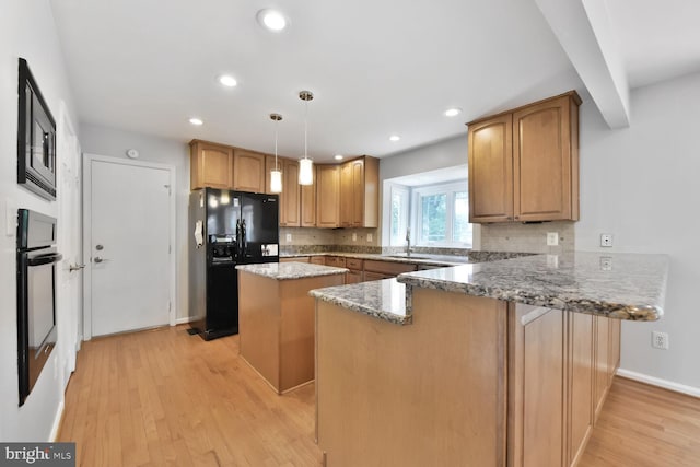 kitchen featuring black fridge with ice dispenser, a peninsula, a kitchen island, wall oven, and light wood-type flooring