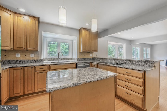 kitchen featuring a sink, light wood-type flooring, a center island, light stone countertops, and recessed lighting