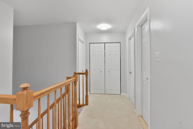 hall with an upstairs landing and light carpet