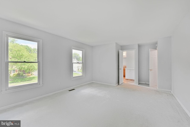 spare room with light carpet and baseboards
