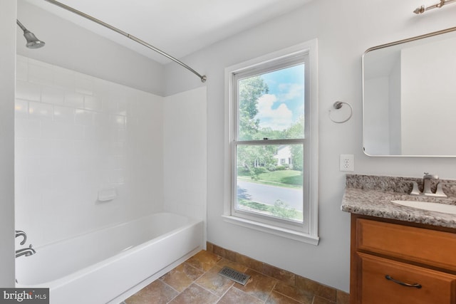 full bathroom featuring vanity, stone finish floors, bathing tub / shower combination, and baseboards