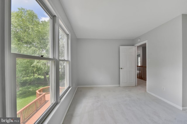 spare room with baseboards and light carpet