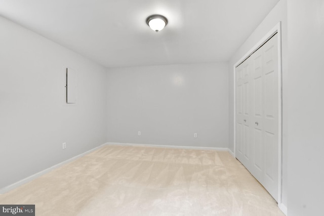unfurnished bedroom with light carpet, a closet, and baseboards