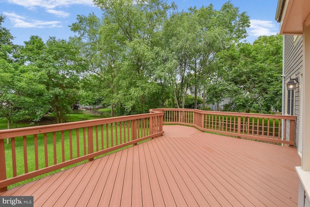 deck featuring a lawn and view of wooded area
