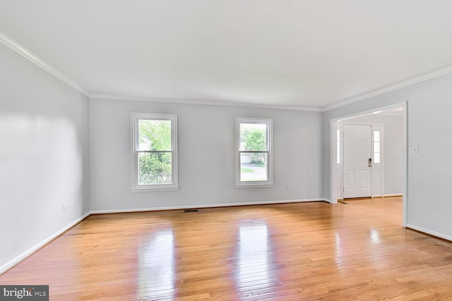 empty room featuring healthy amount of natural light, ornamental molding, light wood-style flooring, and baseboards