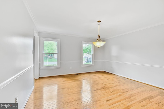 spare room featuring crown molding, wood-type flooring, and baseboards