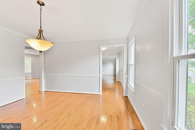 unfurnished dining area with ornamental molding, light wood-style floors, and baseboards