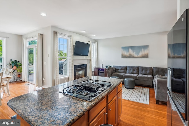 kitchen with black appliances, light wood-style flooring, a center island, open floor plan, and a fireplace