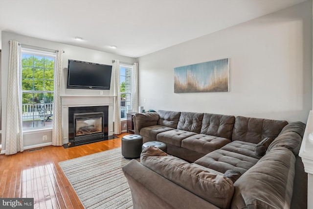 living room with light wood-style floors, plenty of natural light, a fireplace with flush hearth, and baseboards