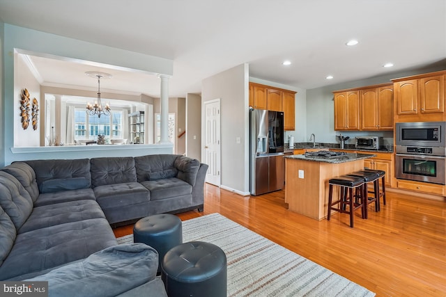 living area with a chandelier, light wood-style floors, recessed lighting, ornate columns, and ornamental molding