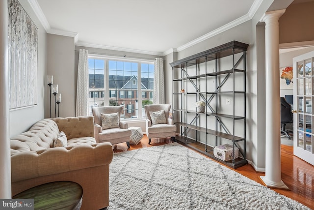 living room with ornate columns, crown molding, and wood finished floors