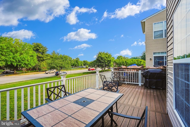 wooden terrace featuring outdoor dining space and a yard