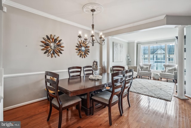 dining area with ornamental molding, ornate columns, hardwood / wood-style floors, a chandelier, and baseboards