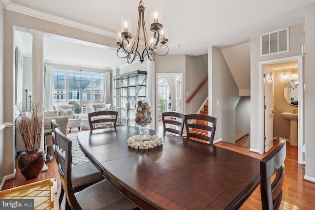 dining space with light wood-type flooring, stairs, ornamental molding, a chandelier, and baseboards