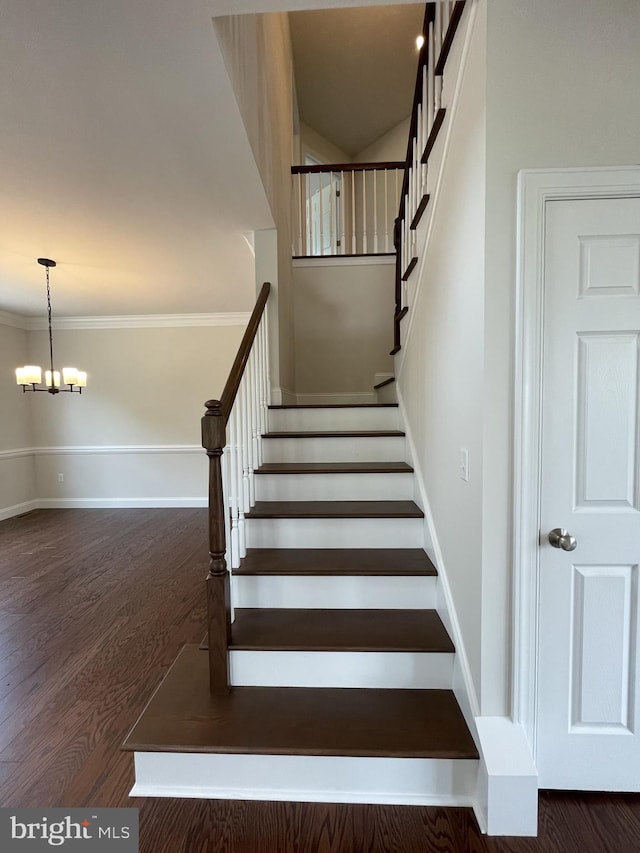 staircase with wood finished floors, baseboards, crown molding, and a chandelier