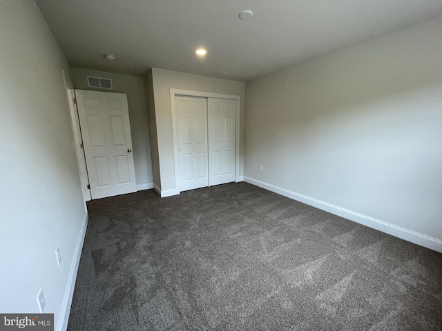 unfurnished bedroom featuring baseboards, dark carpet, a closet, and recessed lighting