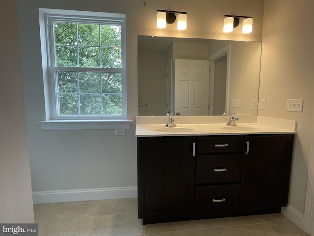 bathroom featuring baseboards, double vanity, and plenty of natural light