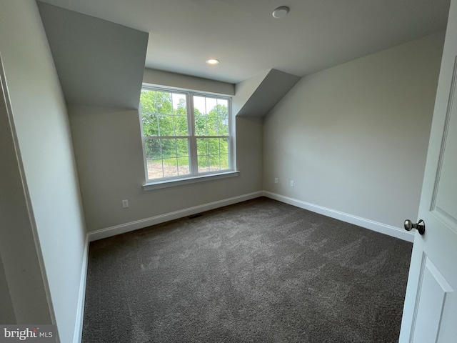 bonus room with dark carpet and baseboards