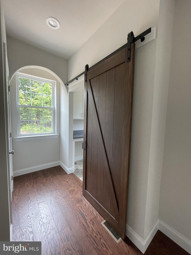 unfurnished bedroom featuring a barn door, wood finished floors, baseboards, and recessed lighting