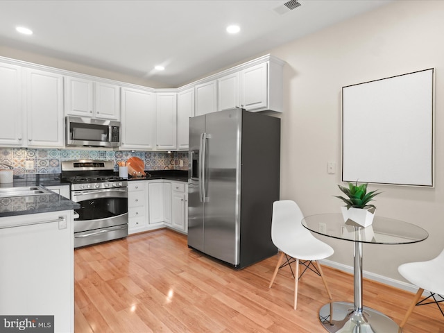 1604 Hunting Creek Dr Unit B, Alexandria, VA 22314 - kitchen featuring appliances with stainless steel finishes, dark countertops, white cabinetry, light wood-style floors, and recessed lighting