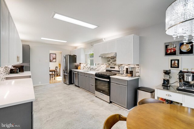 5101 Ampthill Dr, Alexandria, VA 22312 - kitchen with appliances with stainless steel finishes, gray cabinets, backsplash, under cabinet range hood, and light countertops