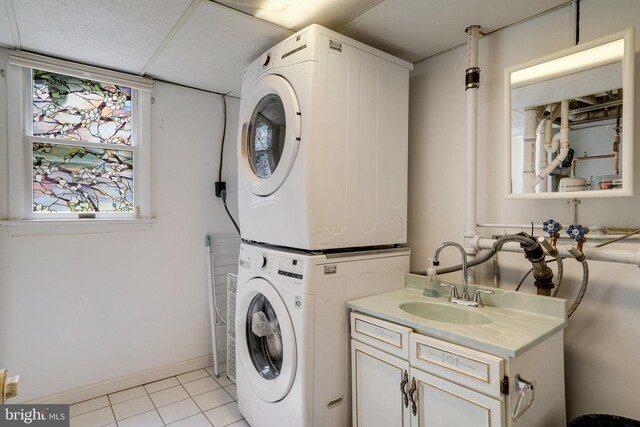 5101 Ampthill Dr, Alexandria, VA 22312 - laundry room featuring estacked washer and dryer, cabinet space, light tile patterned floors, and baseboards