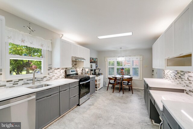 5101 Ampthill Dr, Alexandria, VA 22312 - kitchen featuring appliances with stainless steel finishes, a sink, gray cabinetry, under cabinet range hood, and tasteful backsplash