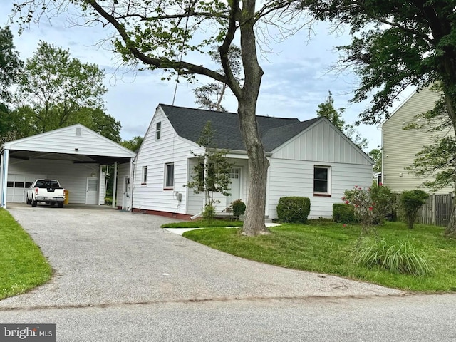 view of front of home featuring board and batten siding, driveway, a carport, and a front yard