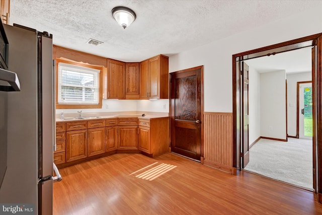 kitchen featuring light wood-style floors, plenty of natural light, light countertops, a textured ceiling, and brown cabinets