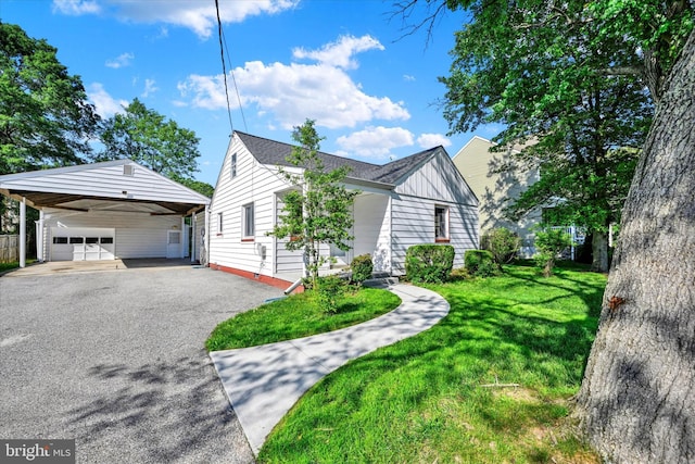 view of home's exterior featuring a yard, a detached garage, asphalt driveway, and board and batten siding
