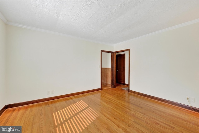 spare room featuring light wood-style flooring, baseboards, a textured ceiling, and crown molding