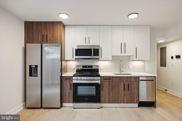 kitchen featuring appliances with stainless steel finishes, a sink, light countertops, baseboards, and decorative backsplash