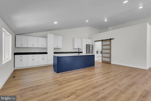 6 Evan Way, Pikesville, MD 21208 - kitchen featuring freestanding refrigerator, lofted ceiling, a barn door, white cabinets, and a center island with sink