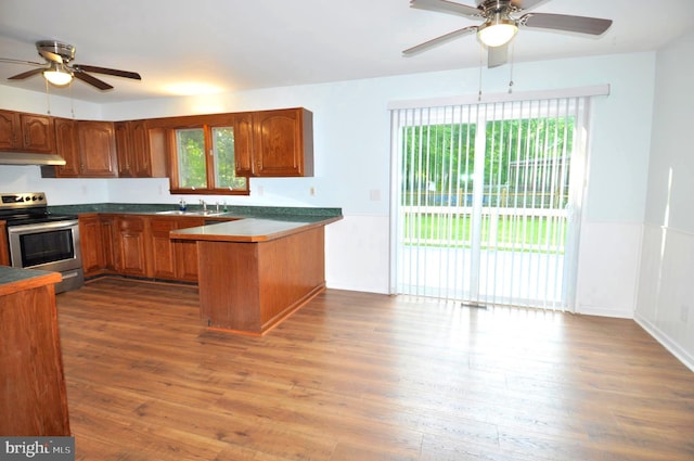 kitchen featuring stainless steel electric range, ceiling fan, a peninsula, and brown cabinets