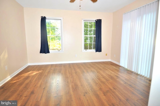 spare room with wood finished floors, ceiling fan, and baseboards