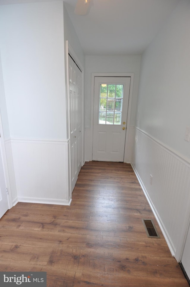 doorway featuring a wainscoted wall and wood finished floors