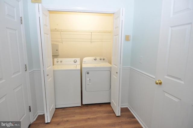 laundry room featuring separate washer and dryer, dark wood-style floors, and a wainscoted wall