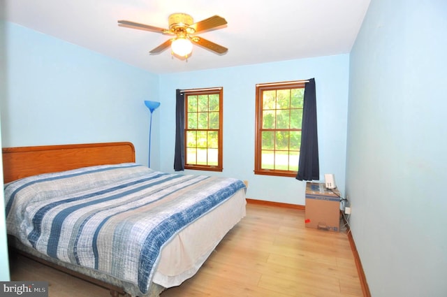 bedroom with light wood finished floors, baseboards, and a ceiling fan
