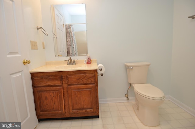 bathroom featuring toilet, vanity, tile patterned floors, and baseboards