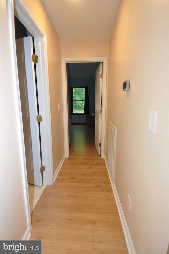 hallway with light wood-style flooring and baseboards